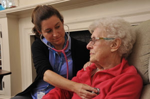 Care Dimensions hospice nurse checks heart of female cardiac patient