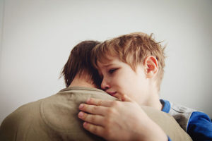 grieving son hugged by his father