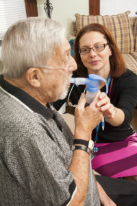 Care Dimensions nurse practitioner Susan Powers assists hospice respiratory patient Tom DeVeau